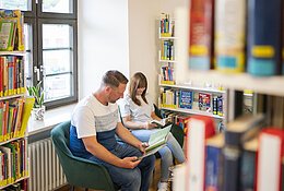 Ein Paar ließt Bücher in der Stadtbücherei.