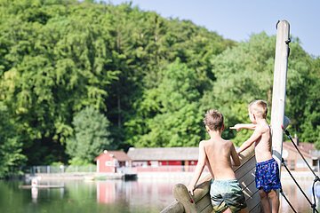 Zwei Kinder stehen auf dem Piratenschiff am Waldsee und zeigen auf das Wasser.